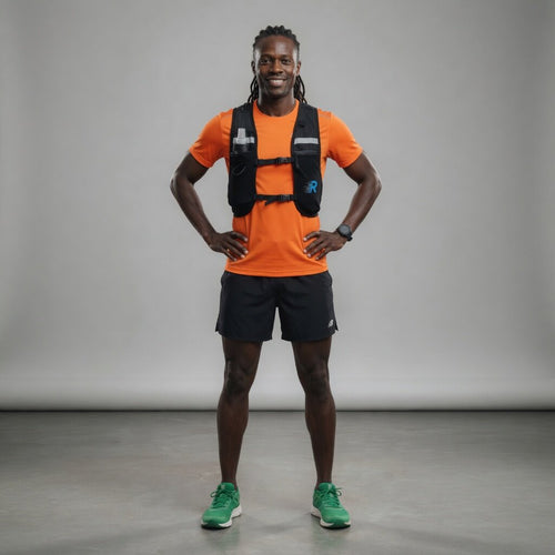 Man wearing an orange shirt, black shorts, and green shoes with a gray background Run With Freedom Challenger Hydration Running Vest Gym Lifestyle Photoshoot